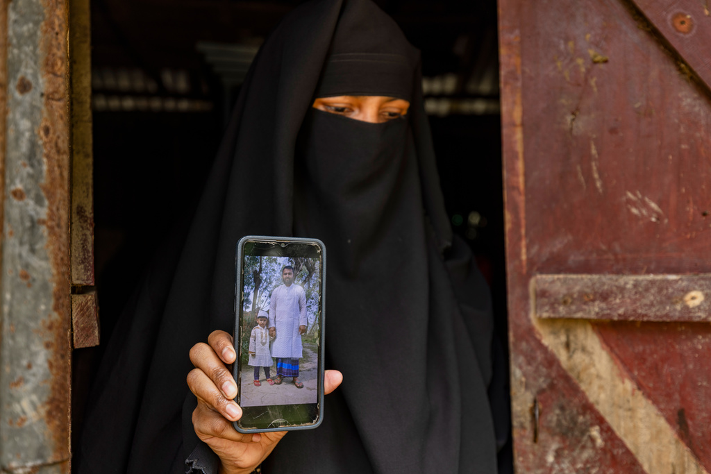 Sadia Islam Sarmin, the wife of Mohammad Abdullah Al Mamun, shows a photo of her late husband and their son on a mobile phone in Rasulpur village, Mymensingh district, Bangladesh, Friday, April 17, 2026. (AP Photo/Rajib Dhar)