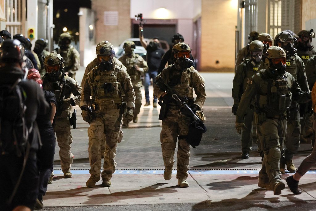 Federal agents walk into the street as people protest outside a U.S. Immigration and Customs Enforcement facility in Portland, Oregon, Friday, Oct. 3, 2025. (AP Photo/Amanda Loman)