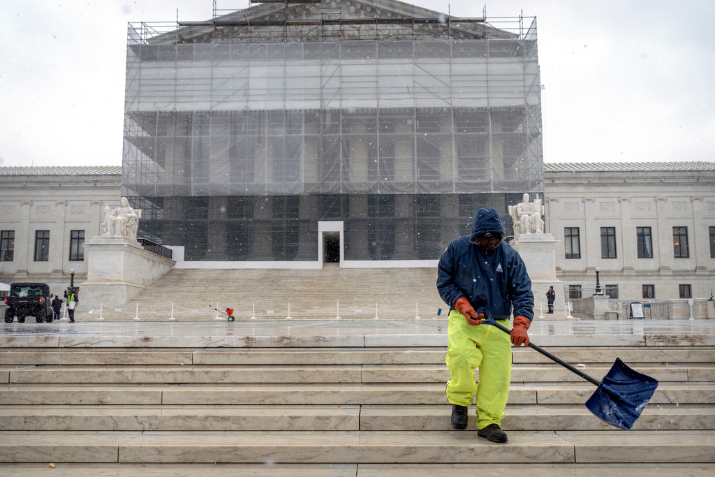 A worker shovels snow and ice in front of the Supreme Court building during the first snowfall of the winter season on Friday, Dec. 5, 2025, in Washington. (AP Photo/Mark Schiefelbein)