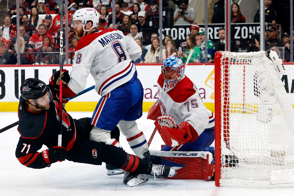 Montréal Canadiens' Mike Matheson (8) takes out Carolina Hurricanes' Taylor Hall (71) in front of Canadiens goaltender Jakub Dobes (75) during the second period in Game 1 of the Eastern Conference finals NHL hockey Stanley Cup playoffs series in Raleigh, N.C., Thursday, May 21, 2026. (AP Photo/Karl DeBlaker)