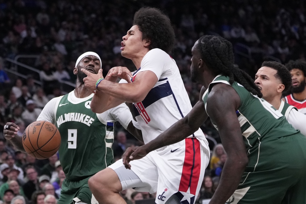 Milwaukee Bucks' Taurean Prince fouls Washington Wizards' Kyshawn George during the first half of an NBA basketball game Wednesday, Oct. 22, 2025, in Milwaukee. (AP Photo/Morry Gash)