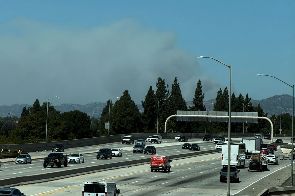 A plume of smoke from the Sandy Fire rises over the 118 freeway Monday, May 18, 2026, in Los Angeles. (AP Photo/Ethan Swope)