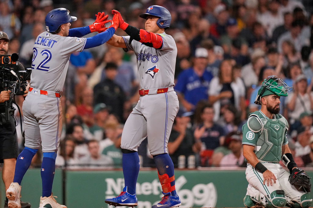 Toronto Blue Jays' Kazuma Okamoto, center, is congratuled by Ernie Clement (22) while passing Boston Red Sox's Connor Wong, right, on his three-run, home run during the seventh inning of a baseball game, Friday, July 24, 2026, in Boston. (AP Photo/Charles Krupa)