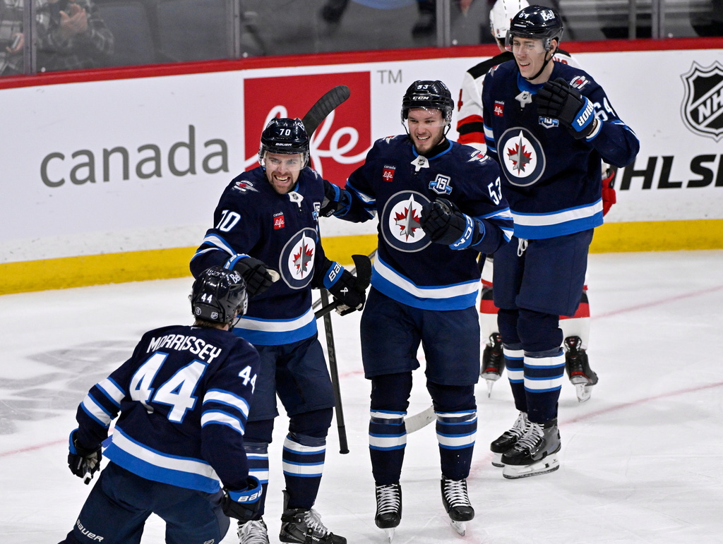 Winnipeg Jets' Tanner Pearson (70) celebrates after the winning goal against the New Jersey Devils with Josh Morrissey (44), Daniel Zhilkin (53) and Logan Stanley (64) in an NHL hockey game in Winnipeg, Manitoba, Sunday, Jan. 11, 2026. (Fred Greenslade/The Canadian Press via AP)