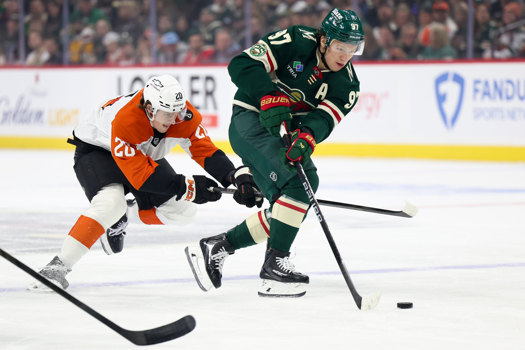 Minnesota Wild left wing Kirill Kaprizov (97) takes the puck up the ice while Philadelphia Flyers left wing Alex Bump (20) defends during the first period of an NHL hockey game Thursday, March 12, 2026, in St. Paul, Minn. (AP Photo/Ellen Schmidt)