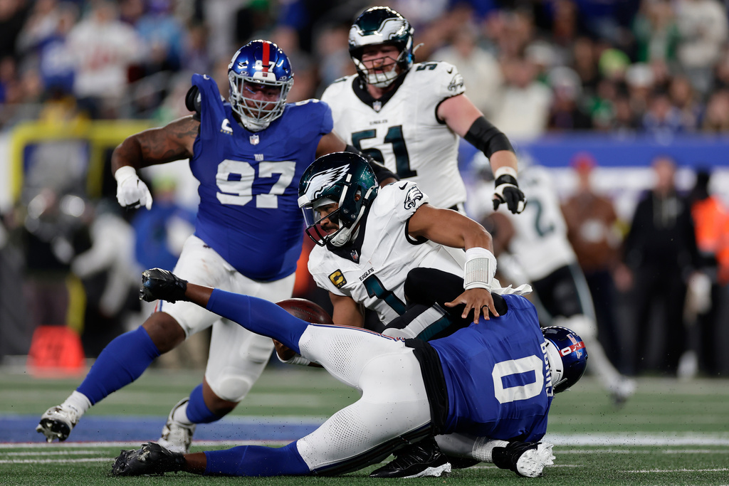 Philadelphia Eagles' Jalen Hurts (1) is sacked by New York Giants' Brian Burns (0) during the second half of an NFL football game Thursday, Oct. 9, 2025, in East Rutherford, N.J. (AP Photo/Adam Hunger)