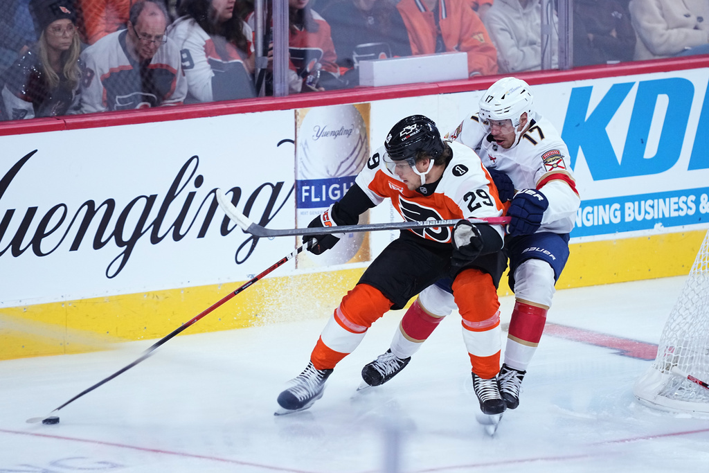 Philadelphia Flyers' Nikita Grebenkin, left, and Florida Panthers' Evan Rodrigues, right, battle for the puck during the first period of an NHL hockey game, Monday, Oct. 13, 2025, in Philadelphia. (AP Photo/Matt Rourke)