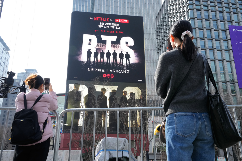 People take photos of a screen promoting a comeback concert of K-pop group BTS at Gwanghwamun Square in Seoul, Wednesday, March 18, 2026. (AP Photo/Ahn Young-joon)