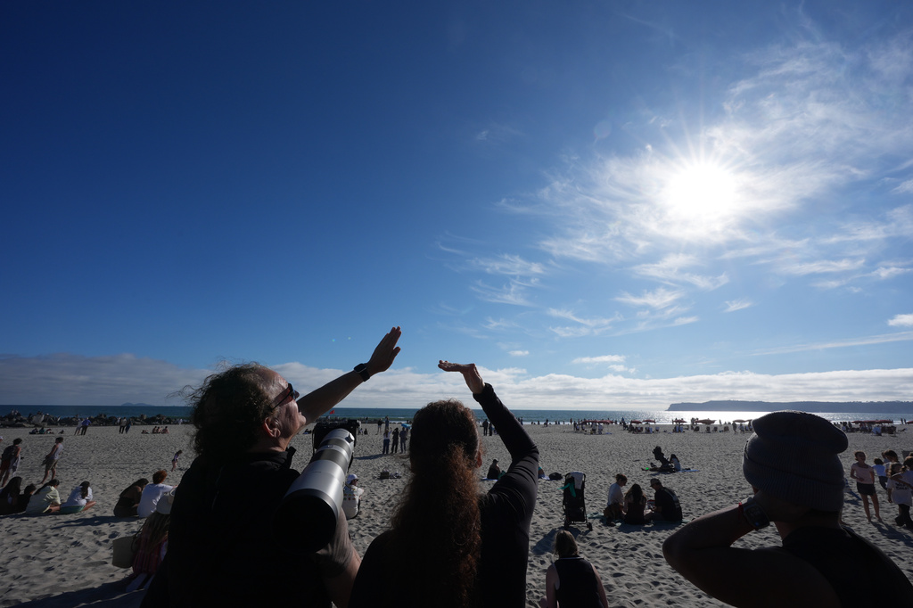 People look up at the sky during a watch party for the return of NASA's Artemis II in Coronado, Calif., Friday, April 10, 2026. (AP Photo/Gregory Bull)