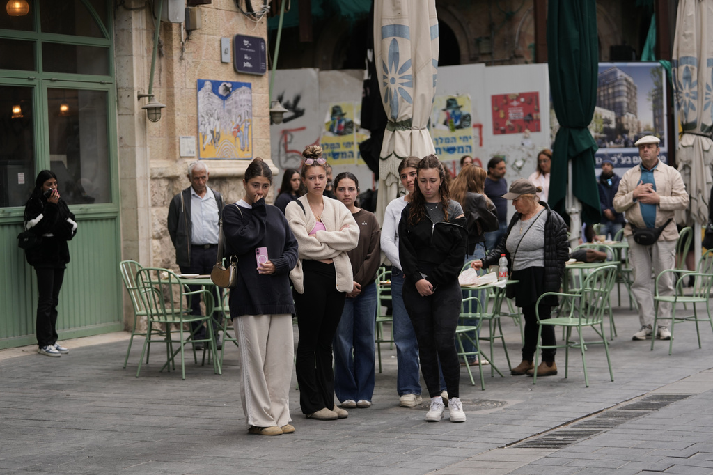 People stand still to observe two minutes of silence as air raid sirens sound, marking Israel's annual Memorial Day for the soldiers who died in the nation's conflicts and victims of nationalistic attacks, in Jerusalem, Tuesday, April 21, 2026. (AP Photo/Mahmoud illean)