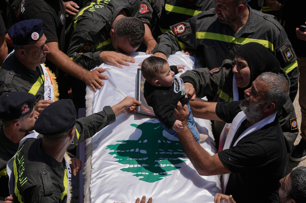A man, right, puts the five months son of Lebanese Civil Defense worker Hussein Ali Satti on his father's coffin who was killed alongside two colleagues in an Israeli strike on Tuesday, during his funeral procession in the southern port city of Tyre, Lebanon, Thursday, April 30, 2026. (AP Photo/Hussein Malla)