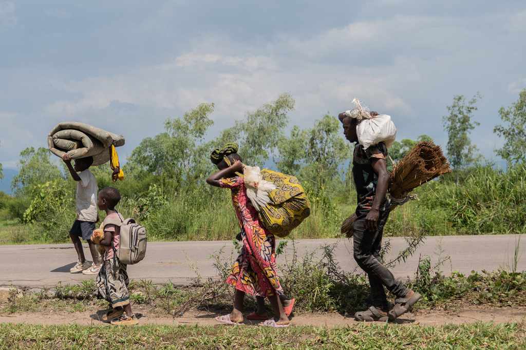 Displaced people who fled the war between FARDC and M23 rebels walk with their belongings as they return to their homes in Luvungi, Democratic Republic of Congo, Saturday, Dec. 13, 2025. (AP Photo/Moses Sawasawa)