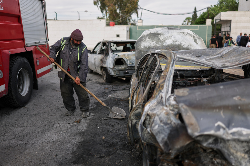 A worker cleans near damaged cars at the site of an explosion outside a Defense Ministry building in Damascus, Syria, Tuesday, May 19, 2026. (AP Photo/Ghaith Alsayed)