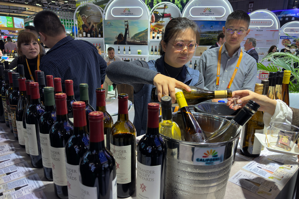 An exhibitor pours wine for visitors at the exhibition booth of American Food and Agriculture during the China International Import Expo, in Shanghai, China, Thursday, Nov. 6, 2025. (AP Photo/Wayne Zhang)