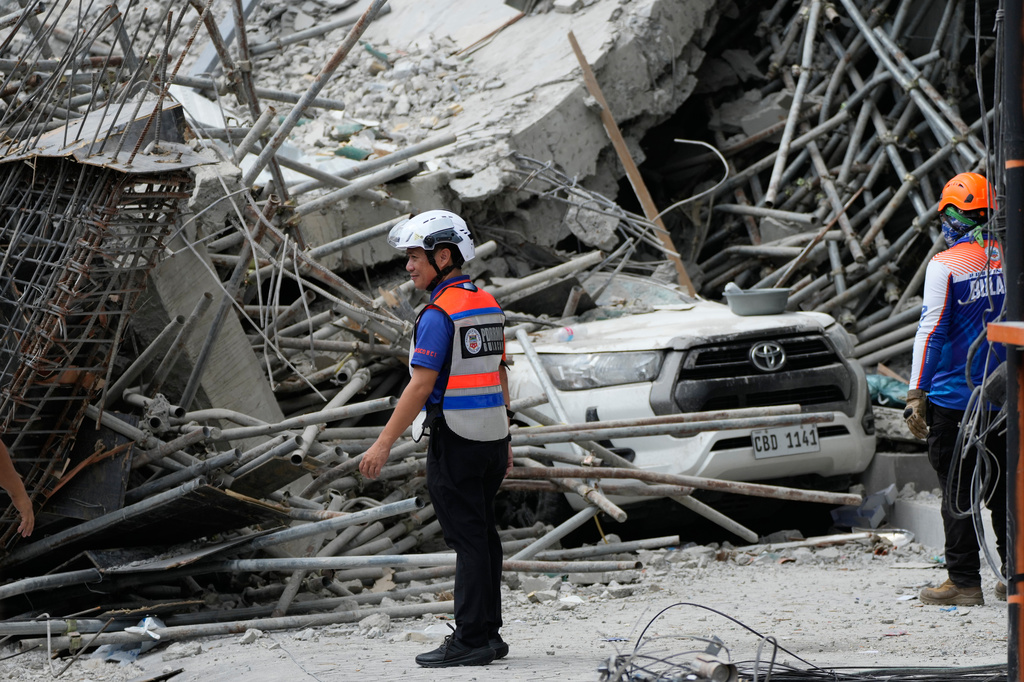 Rescuers stand beside ruins as search operations continue at a collapsed building in Angeles city in Pampanga province, north of Manila, Monday, May 25, 2026. (AP Photo/Aaron Favila)