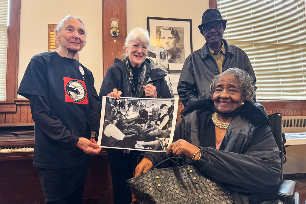 Doris Wilson, right, accompanied by her son, right rear, holds photo with Dr. June Finer, left and Jeannine Herron, center, who was married to the Civil Rights photographer Matt Herron, Dec. 4, 2025. Marion, Ala. (Safiyah Riddle/AP)