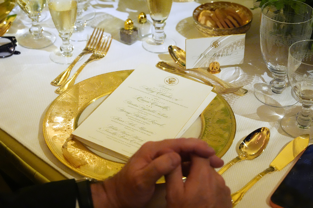A table setting is seen as Britain's King Charles III speaks during a State Dinner with President Donald Trump, first lady Melania Trump and Queen Camilla in the East Room of the White House State Dinner Tuesday, April 28, 2026, in Washington. (AP Photo/Alex Brandon)