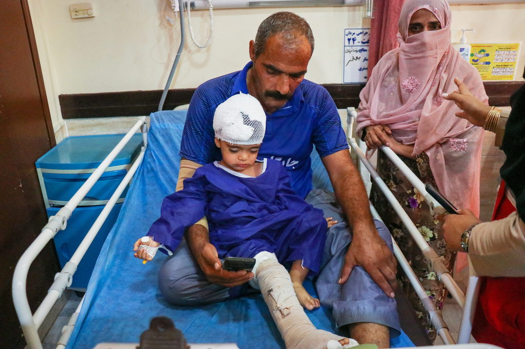 A man sits with a child injured, according to Iranian media, in a strike on a home where a wedding was being held in Kuhestak, southern Iran, at a hospital in Menab, Iran, early Wednesday, Sept.2, 2026. (Razieh Poudat/ISNA via AP)
