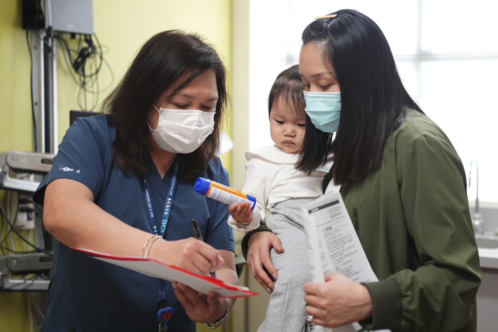 Lead medical assistant Maria Teresa Diocales goes over vaccine information with Huanyu Zhen as her daughter Lena Kuang, 1, looks on at International Community Health Services, Wednesday, Sept. 10, 2025, in Seattle. (AP Photo/Lindsey Wasson)