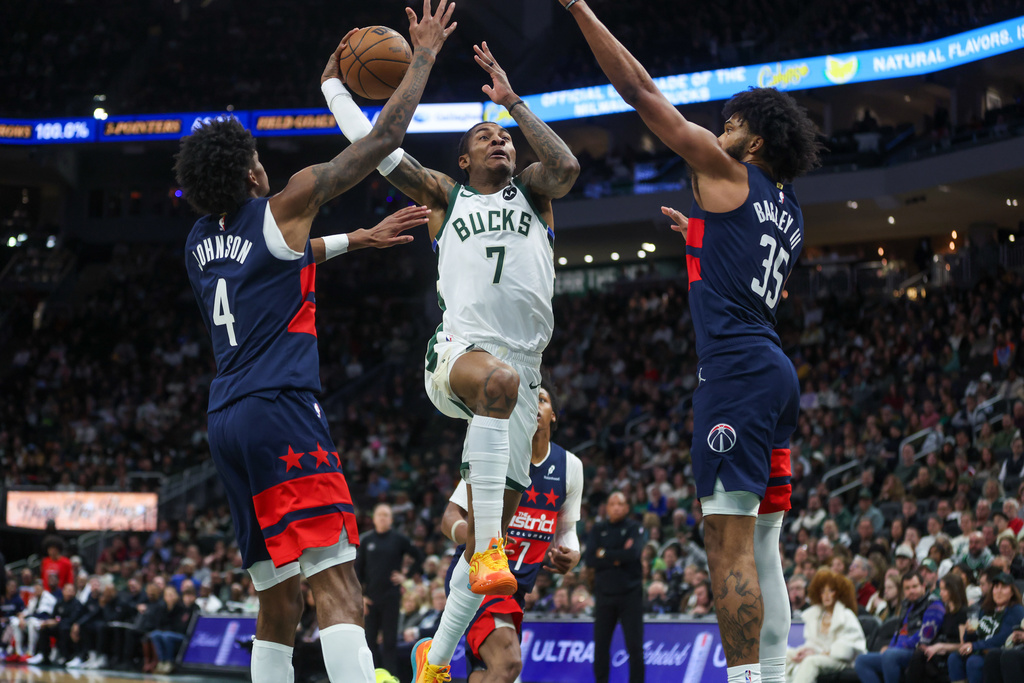 Milwaukee Bucks' Kevin Porter Jr. drives to the basket between Washington Wizards' AJ Johnson and Marvin Bagley III during the first half of an NBA basketball game, Wednesday, Dec. 31, 2025, in Milwaukee. (AP Photo/Kylie Bridenhagen)