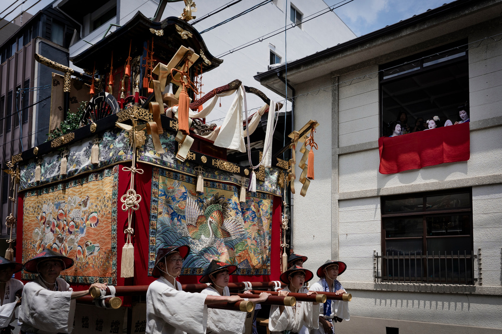A festival float passes by maikos and geikos watching one of the main parades of Shinto's Gion Matsuri festival in Kyoto, western Japan, Friday, July 17, 2026. (AP Photo/Fred Mery)