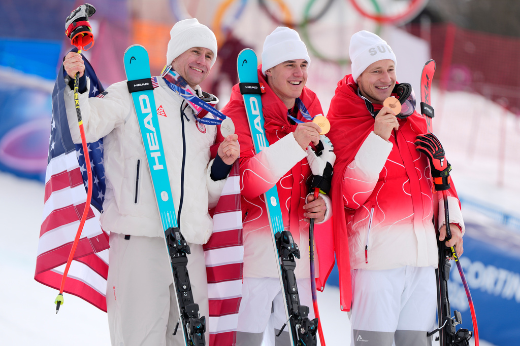 Switzerland's Franjo von Allmen, gold medalist in an alpine ski, men's super-G race, center, is flanked by silver medalist United States' Ryan Cochran Siegle, left, and bronze medalist Switzerland's Marco Odermatt, at the 2026 Winter Olympics, in Bormio, Italy, Wednesday, Feb. 11, 2026.(AP Photo/Julia Demaree Nikhinson)