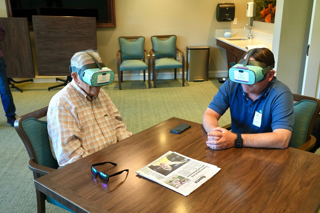 Jim Holtshouse and his son, Mike Holtshouse, watch video through Rendever virtual-reality headsets at the Forum at Rancho San Antonio retirement community in Cupertino, Calif. on June 11, 2025. (AP Photo/Terry Chea)