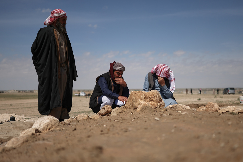Mourners kneel by the graves of six people from the Al-Jalib family, who were killed Wednesday in Israeli strikes in Beirut, after their burial in the village of al-Sour, Deir al-Zour province, northeastern Syria, Saturday, April 11, 2026. (AP Photo/Ghaith Alsayed)