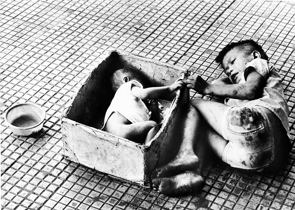 FILE - This 1973 file photo shows Tran Thie Het Nhanny lying in a cardboard box next to her brother, who begged on the streets of Saigon, Vietnam. (AP Photo/Chick Harrity, File)