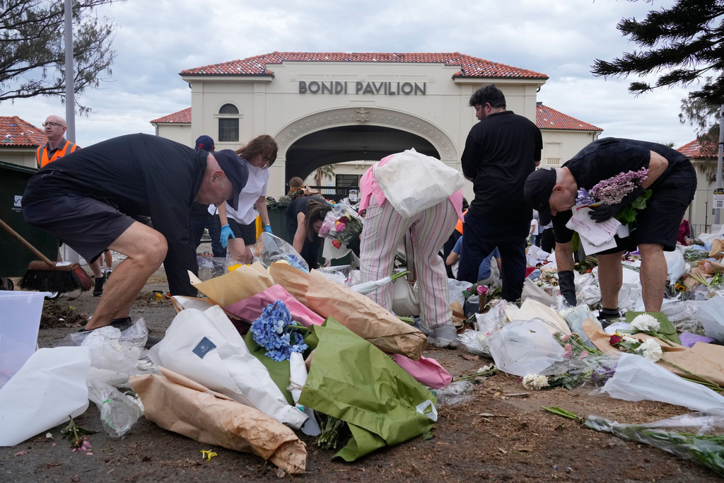 Workers gather floral tributes, messages of support and items left as a memorial is dismantled in Sydney, Monday, Dec. 22, 2025, a week after an attack on a Jewish festival that left 15 dead. (AP Photo/Rick Rycroft)