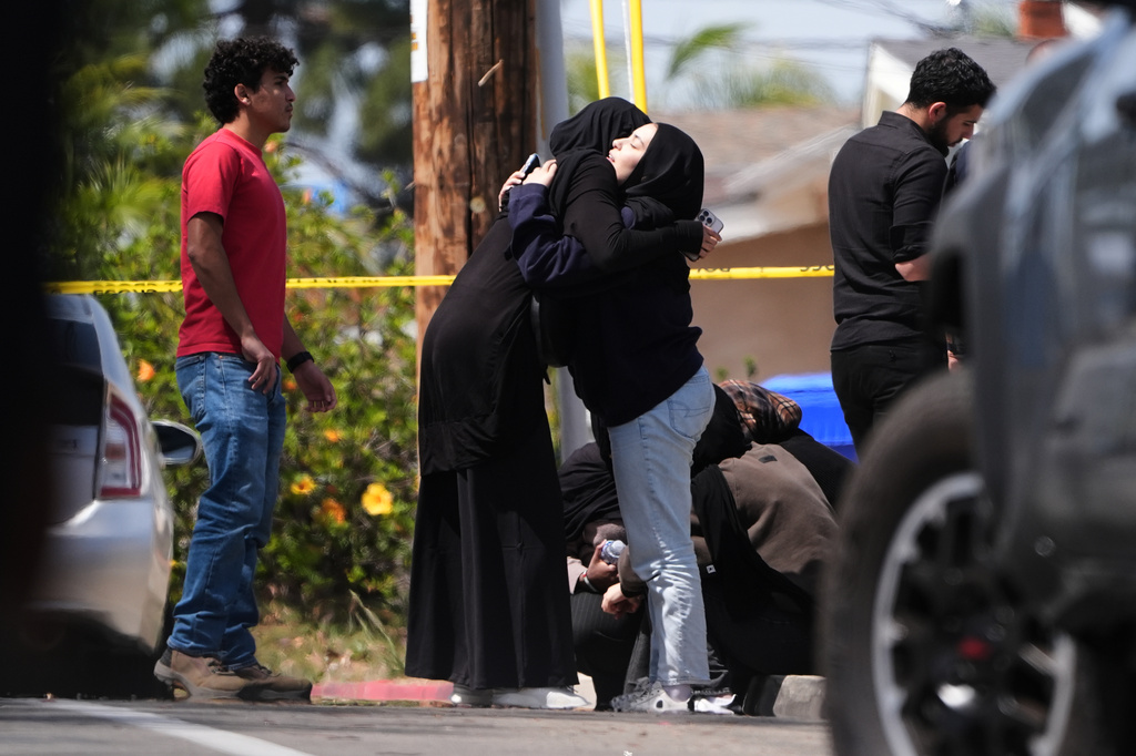 FILE - People embrace near the scene of a shooting outside the Islamic Center in San Diego, May 18, 2026, (AP Photo/Gregory Bull, File)