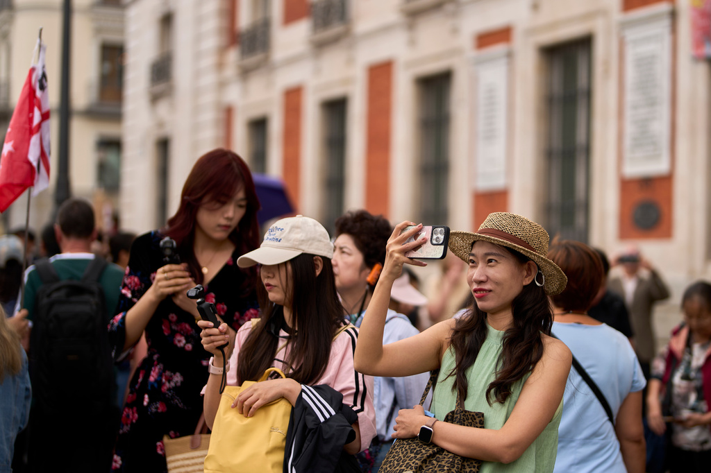 Tourists take pictures of protesters camping during a protest at Sol Square following the eviction last Wednesday of 87-year-old Maricarmen as they demand stronger laws to protect renters in Madrid, Spain, Monday, Sept. 28, 2026. (AP Photo/Manu Fernandez)
