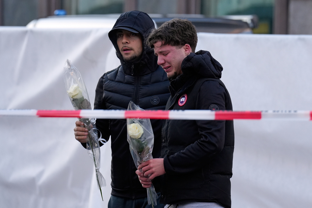 People bring flowers to the sealed off Le Constellation bar in Crans-Montana, Swiss Alps, Switzerland, Saturday, Jan. 3, 2026, where a devastating fire left dead and injured during the New Year's celebrations. (AP Photo/Baz Ratner)