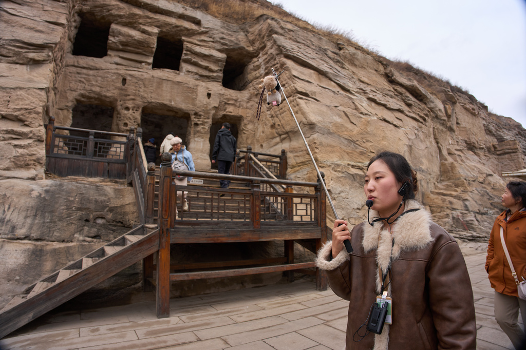 A tour guide leads a group tourists as they visit the Yungang Grottoes in Datong, China, Friday, March 13, 2026. (AP Photo/Ng Han Guan)