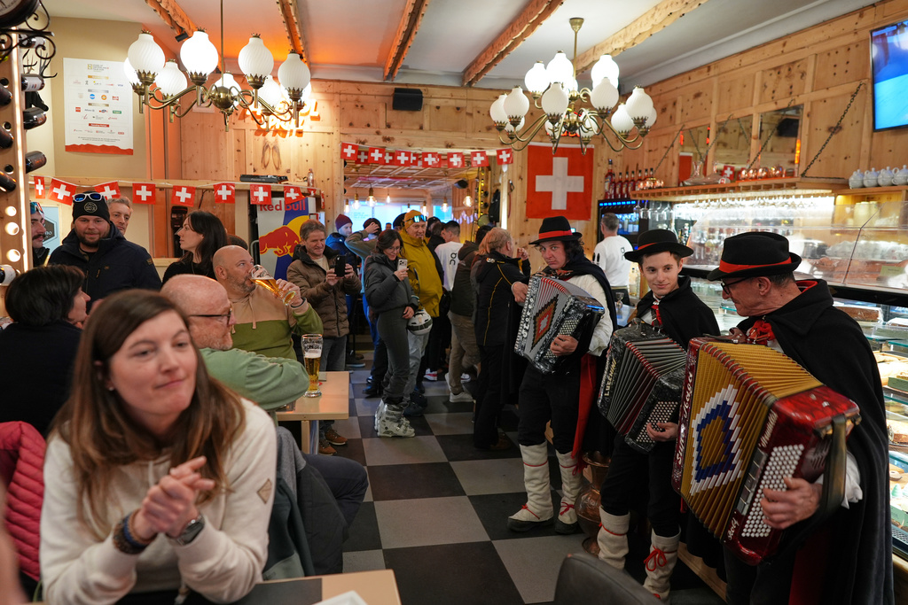 Accordion players, from right, Flavio Bottoni, Alberto Canclini, and Marco Compagnoni stop to perform a few songs inside a bar as they roam the streets of Bormio, Italy, as part of the festivities for the 2026 Winter Olympics, Sunday, Feb. 8, 2026. (AP Photo/Rebecca Blackwell)