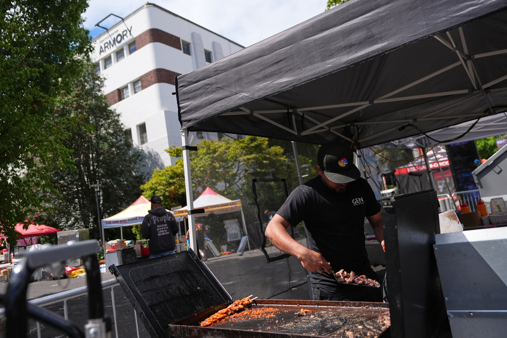 A vendor throws away food while cleaning up the day after a shooting at Seattle Center during the Bite of Seattle food festival, Monday, July 27, 2026, in Seattle. (AP Photo/Lindsey Wasson)