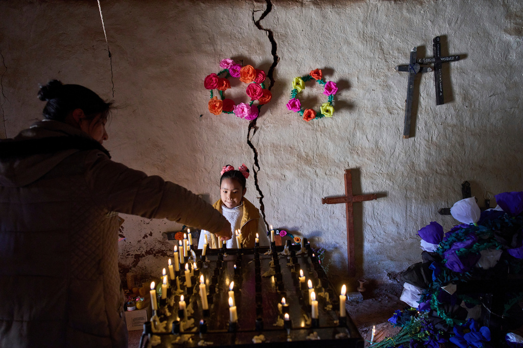 Nina Valentina Nieva helps her uncle Lorena Plaza light a candle in memory of her mother, Lorena Luca, inside a chapel at the cemetery during Day of the Dead celebrations in Susques, Jujuy province, Argentina, Saturday, Nov. 1, 2025. (AP Photo/Rodrigo Abd)