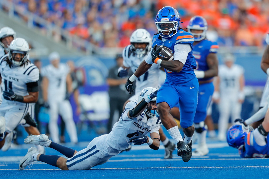 Boise State running back Dylan Riley (0) breaks away from the grasp of Utah State safety Brevin Hamblin (4) on a 33-yard touchdown run in the first half of an NCAA college football game, Saturday, Oct. 3, 2026, in Boise, Idaho. (AP Photo/Steve Conner)