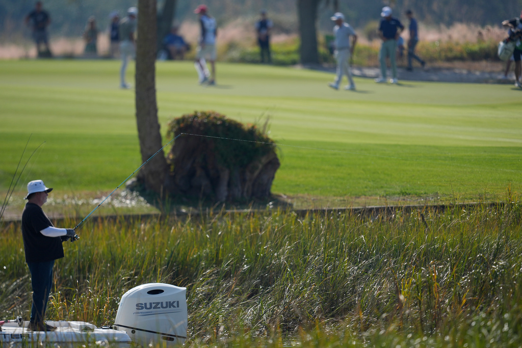 A man fishes off a boat near the 12th green during the second round of the RSM Classic golf tournament, Friday, Nov. 21, 2025, in St. Simons Island, Ga. (AP Photo/Mike Stewart)