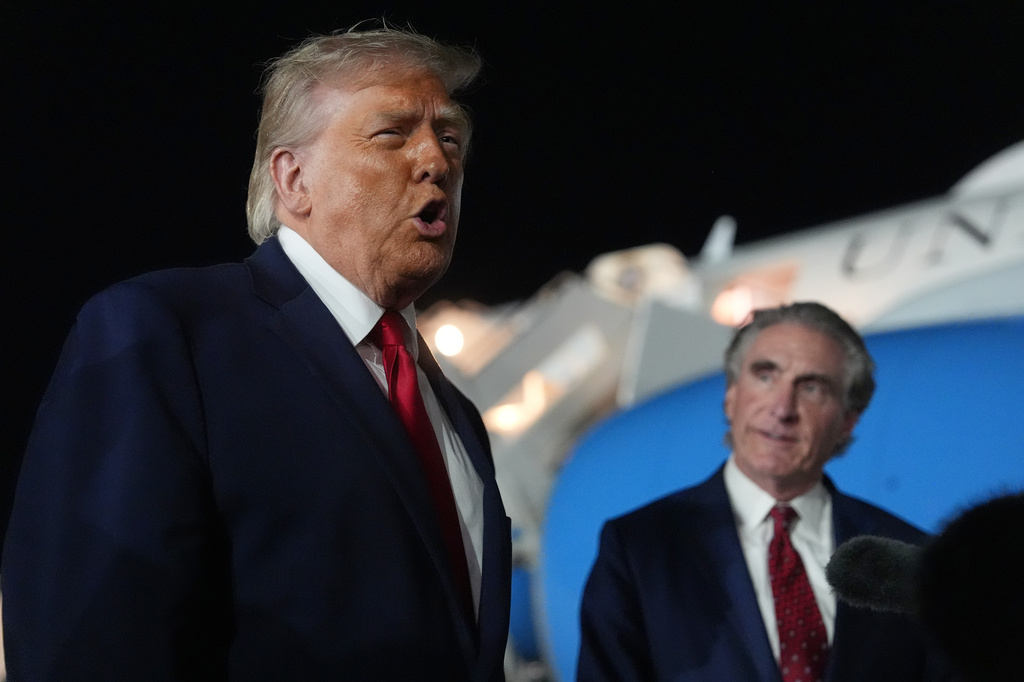 President Donald Trump talks with reporters before boarding Air Force One at John F. Kennedy International Airport in New York, early Tuesday, June 9, 2026, as Interior Secretary Doug Burgum listens. (AP Photo/Mark Schiefelbein)