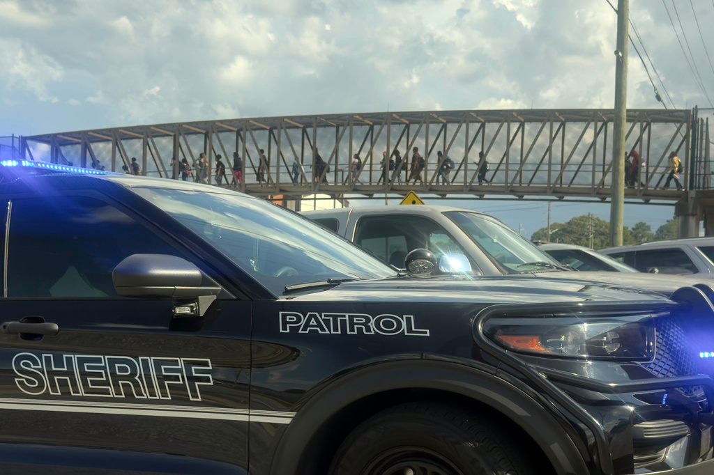 Students leave Warner Robins High School as Houston County Sheriff vehicles remain on the scene after a shooting at the school Wednesday, Aug. 12, 2026, in Warner Robins, Ga. (Joe Kovac/Atlanta Journal-Constitution via AP)