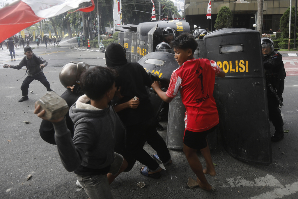 People throw rocks at the police during a protest following the death of a delivery rider in clashes between riot police and students protesting against lawmakers' allowances, in Medan, North Sumatra, Indonesia, Friday, Aug. 29, 2025. (AP Photo/Binsar Bakkara)