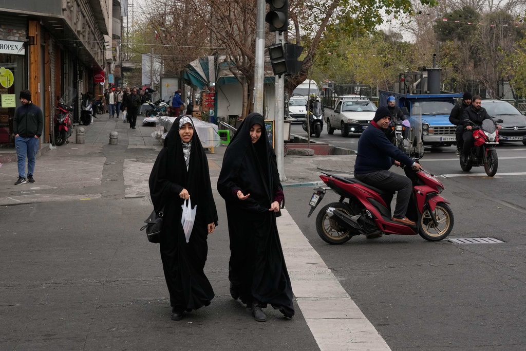 Women cross an intersection in downtown Tehran, Iran, Thursday, Jan. 15, 2026. (AP Photo/Vahid Salemi)