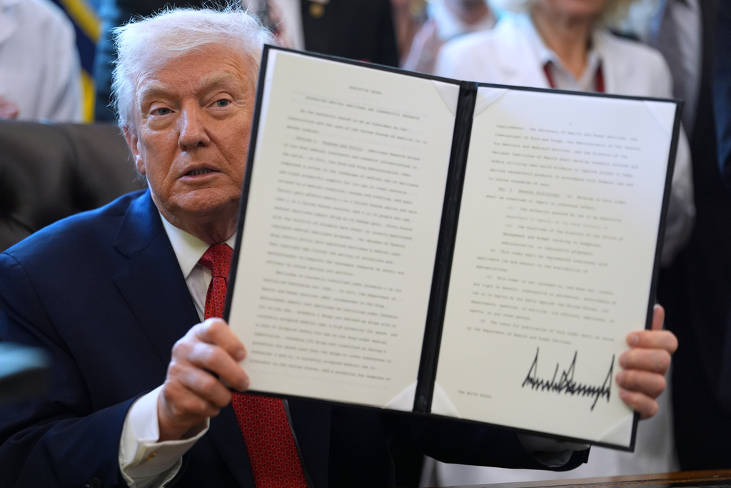 President Donald Trump displays an executive order reclassifying marijuana as a less dangerous drug in the Oval Office of the White House, Thursday, Dec. 18, 2025, in Washington. (AP Photo/Evan Vucci)