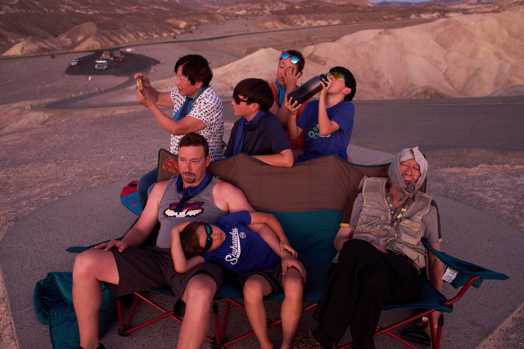 FILE - Joe Chyuwei, right, Addison Black, front center, James Black, front left, and back row from left, Helen Chyuwei, Jameson Black, Grace Chyuwei and Grayson Black watch the sunset in the heat at Zabriskie Point, Aug. 3, 2025, in Death Valley National Park, Calif. (AP Photo/John Locher, File)