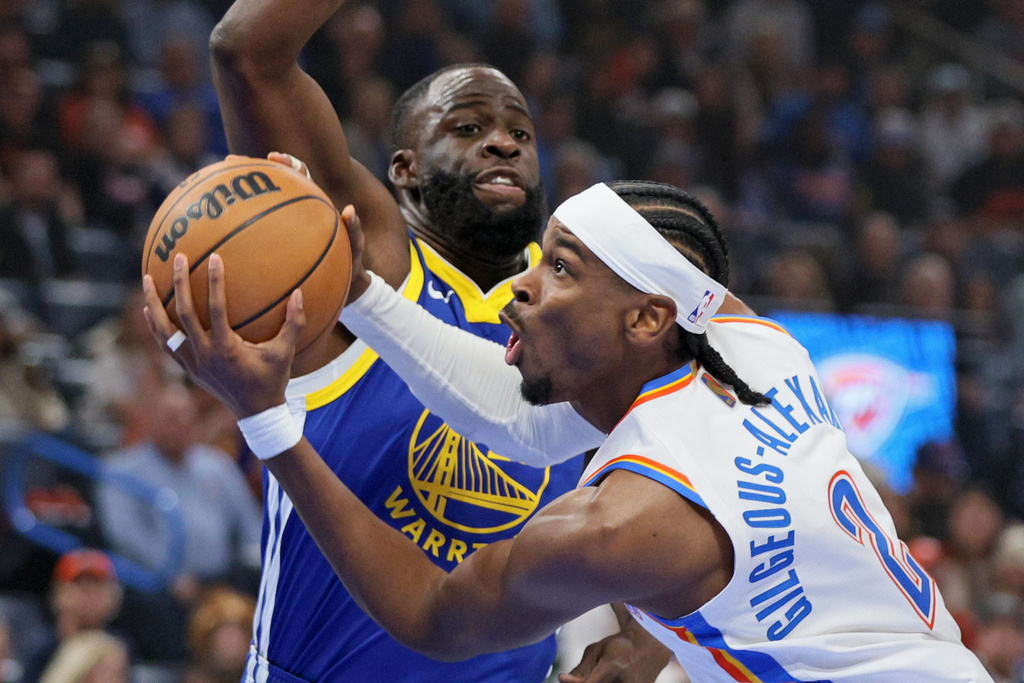 Oklahoma City Thunder guard Shai Gilgeous-Alexander, front, goes to the basket against Golden State Warriors forward Draymond Green, back, during the first half of an NBA basketball game Saturday, March 7, 2026, in Oklahoma City. (AP Photo/Nate Billings)