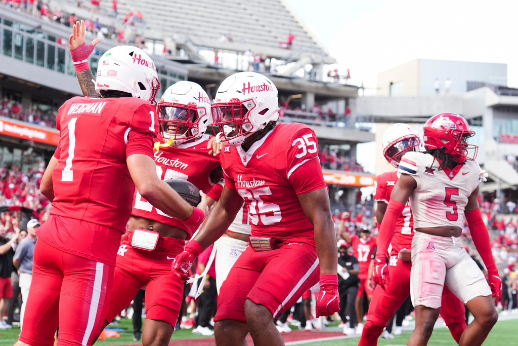 Houston running back DJ Butler, second from left, and tight end Kaleb Thomas celebrate, center, celebrate after quarterback Conner Weigman's 10-yard touchdown run during the first half of an NCAA college football game against Arizona, Saturday, Oct. 18, 2025, in Houston. (Jason Fochtman/Houston Chronicle via AP)