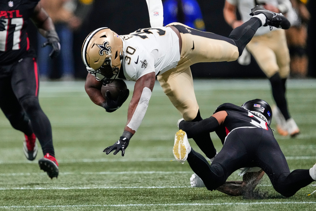 New Orleans Saints running back Audric Estime (30) is tripped up by Atlanta Falcons safety Jessie Bates III (3) in the first half of an NFL football game, Sunday, Jan. 4, 2026, in Atlanta. (AP Photo/Brynn Anderson)