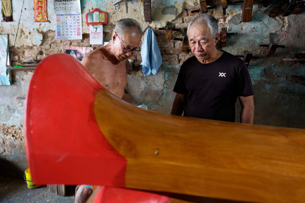Brothers Goh Khuay Par, left, and Goh Khuay Hou inspect a completed Mei Hua coffin at their family's workshop in Muar, Malaysia, Monday, Sept. 7, 2026. (AP Photo/Vincent Thian)