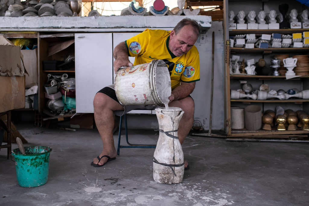 Jarbas Meneghini Carlini demonstrates how he makes FIFA World Cup trophy replicas at his home in Rio de Janeiro, Friday, May 15, 2026. (AP Photo/Bruna Prado)
